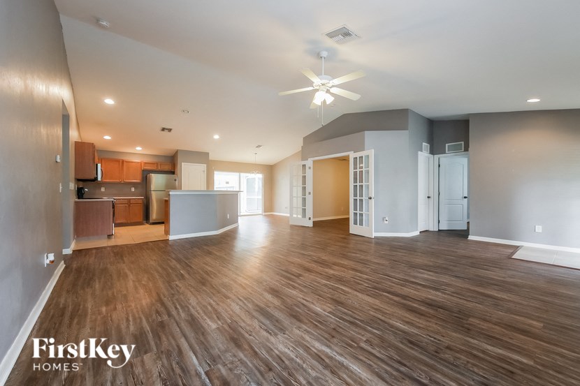 a living room and kitchen with wood flooring and a ceiling fan