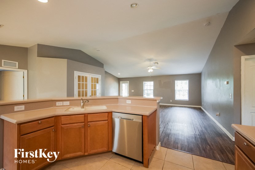 an empty kitchen with an empty living room in the background