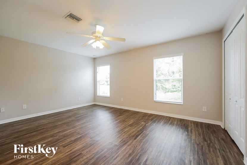 an empty living room with wood flooring and a ceiling fan