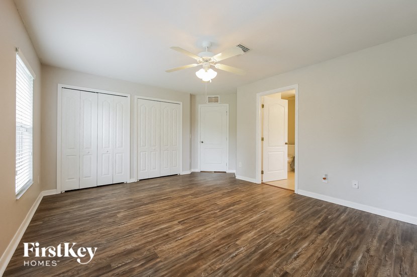 an empty living room with wood flooring and a ceiling fan