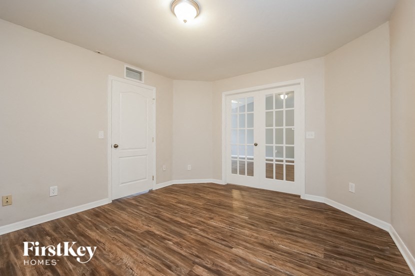 an empty living room with a white door and wood flooring