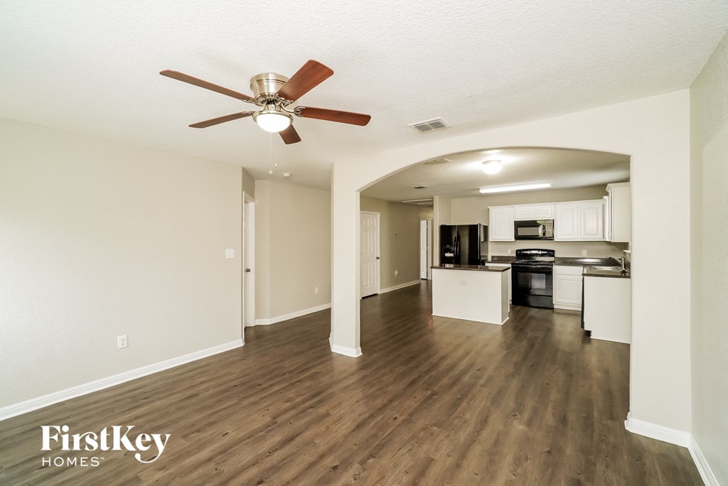 A spacious kitchen and living room with a wood floor and a ceiling fan.