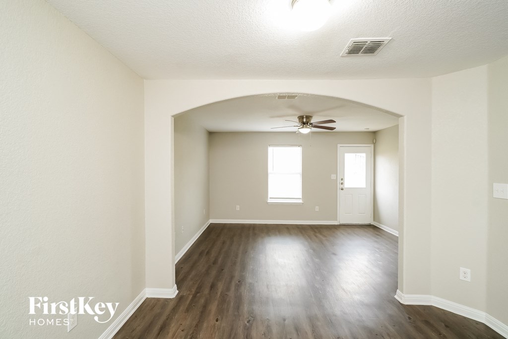 A spacious room with wood flooring and a ceiling fan.