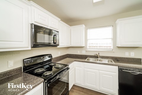 A kitchen with white cabinets and a black stove top oven.
