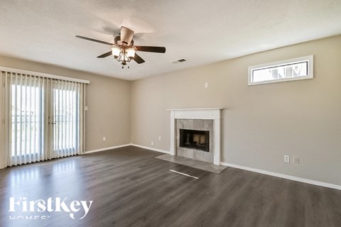 A spacious living room with a fireplace and a ceiling fan.