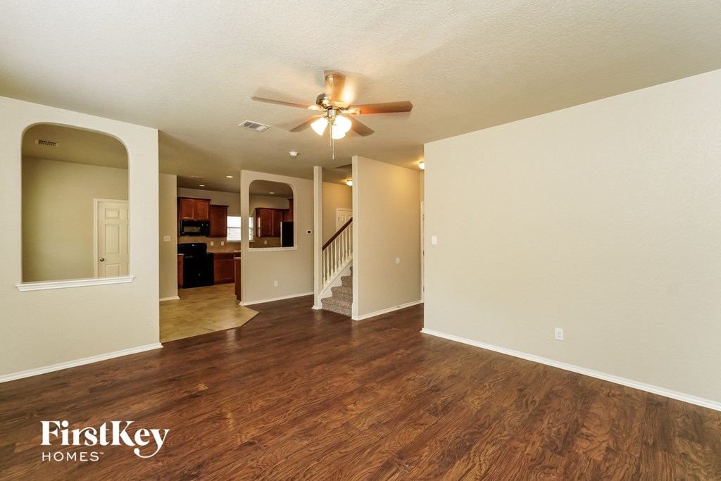 an empty living room with a ceiling fan and hard wood floors