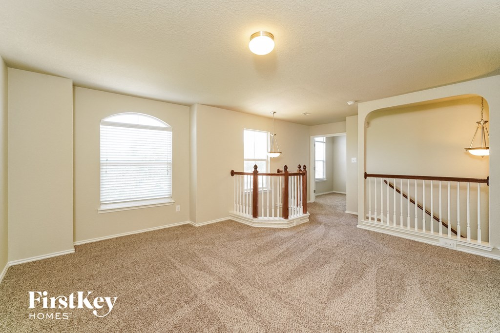 an empty living room with a staircase and a large window