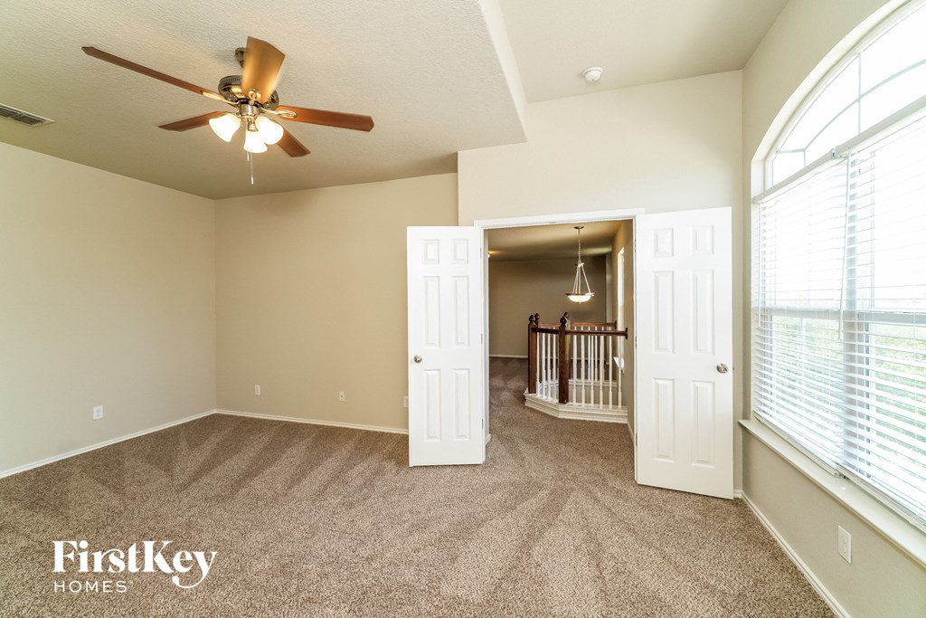 an empty living room with a ceiling fan and a baby crib