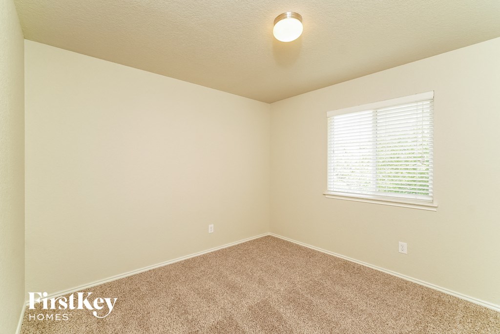 the spacious bedroom has carpeting and a large window