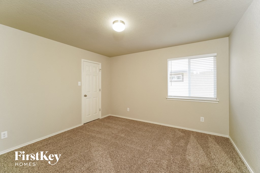 the spacious bedroom with carpeted flooring and a window
