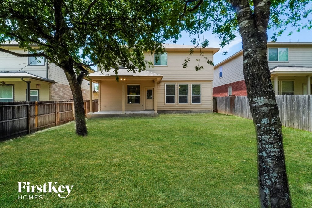a backyard with two trees and a house with a fence