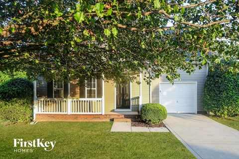 A house with a white garage door is shown with a tree in front.
