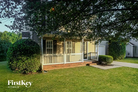 A house with a porch and a tree in front of it.