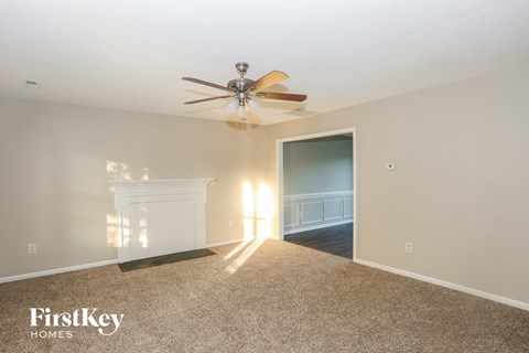 A room with a carpet floor and a ceiling fan.