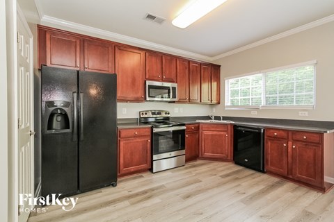 A kitchen with wooden cabinets and a black fridge.