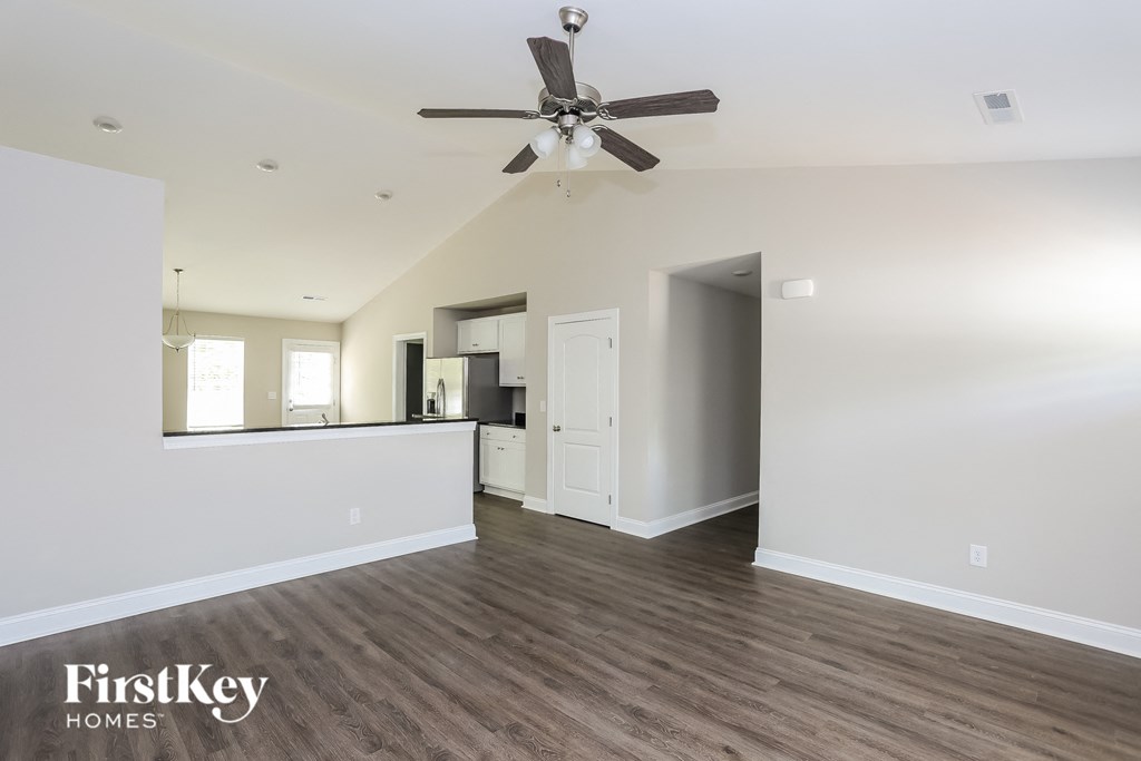 a living room with white walls and a ceiling fan