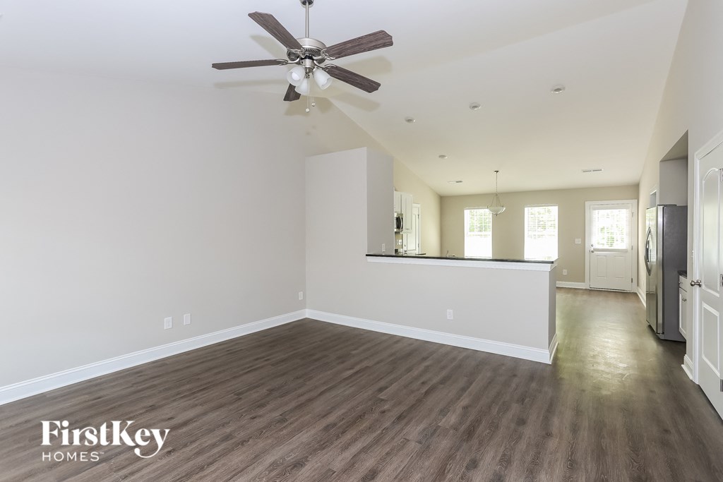 an empty living room with white walls and a ceiling fan