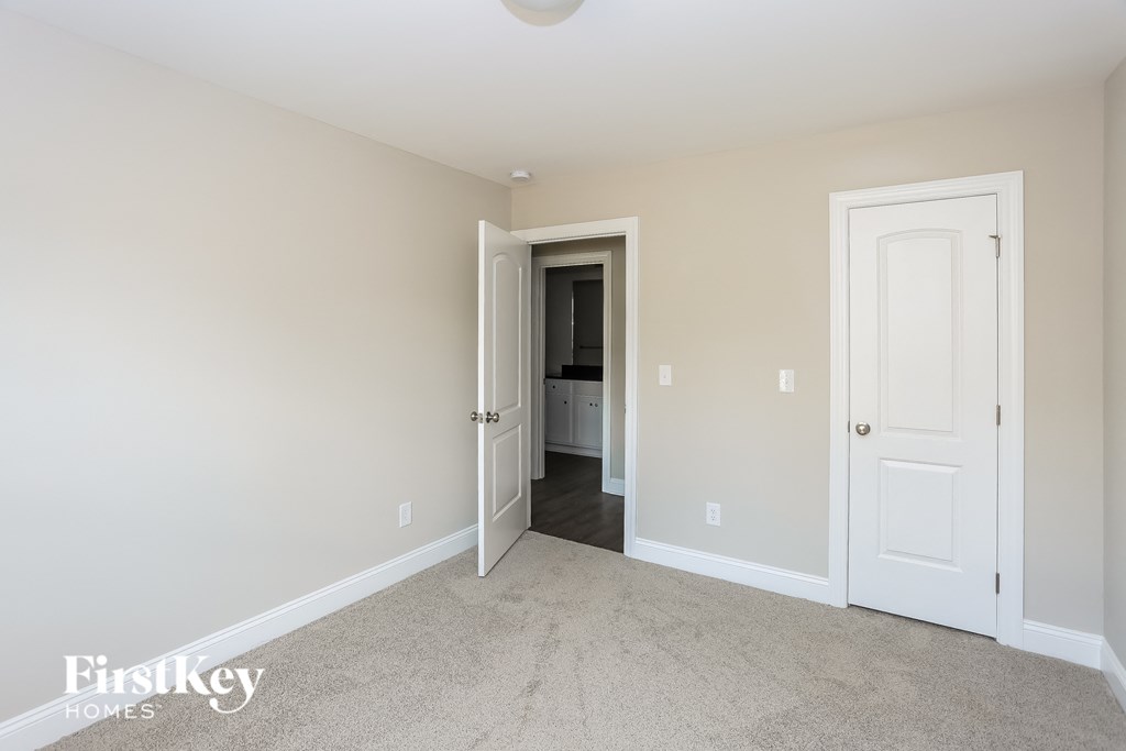 a master bedroom with a carpeted floor and a door to the bathroom
