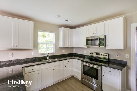 A kitchen with white cabinets and black countertops.