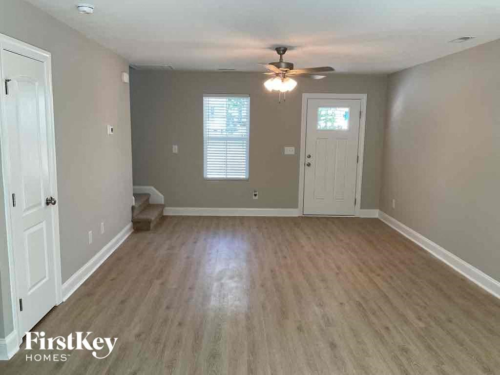 A room with a ceiling fan and light fixture, two doors, and a window with blinds.