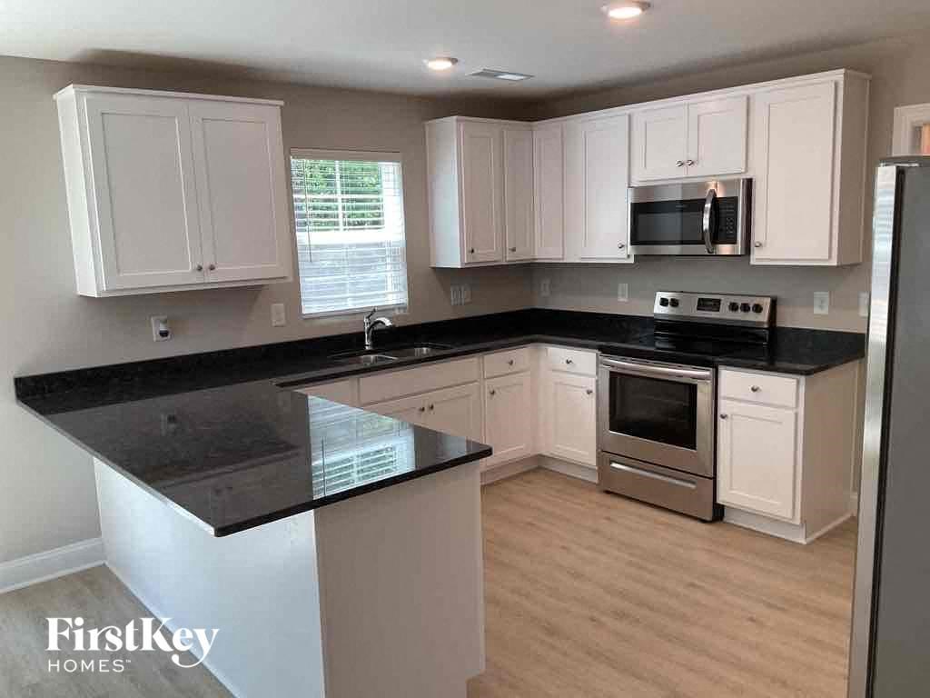 A kitchen with white cabinets and black countertops.