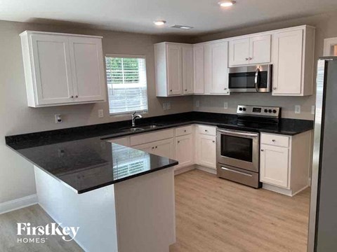 A kitchen with white cabinets and black countertops.