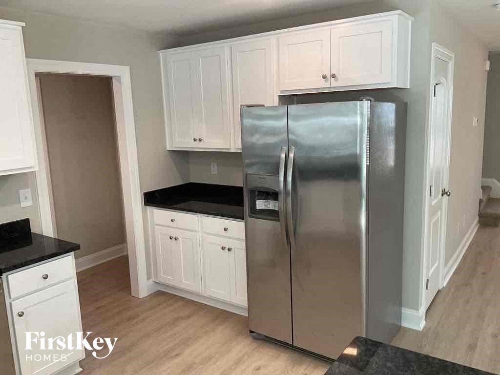 A kitchen with a stainless steel refrigerator and white cabinets.
