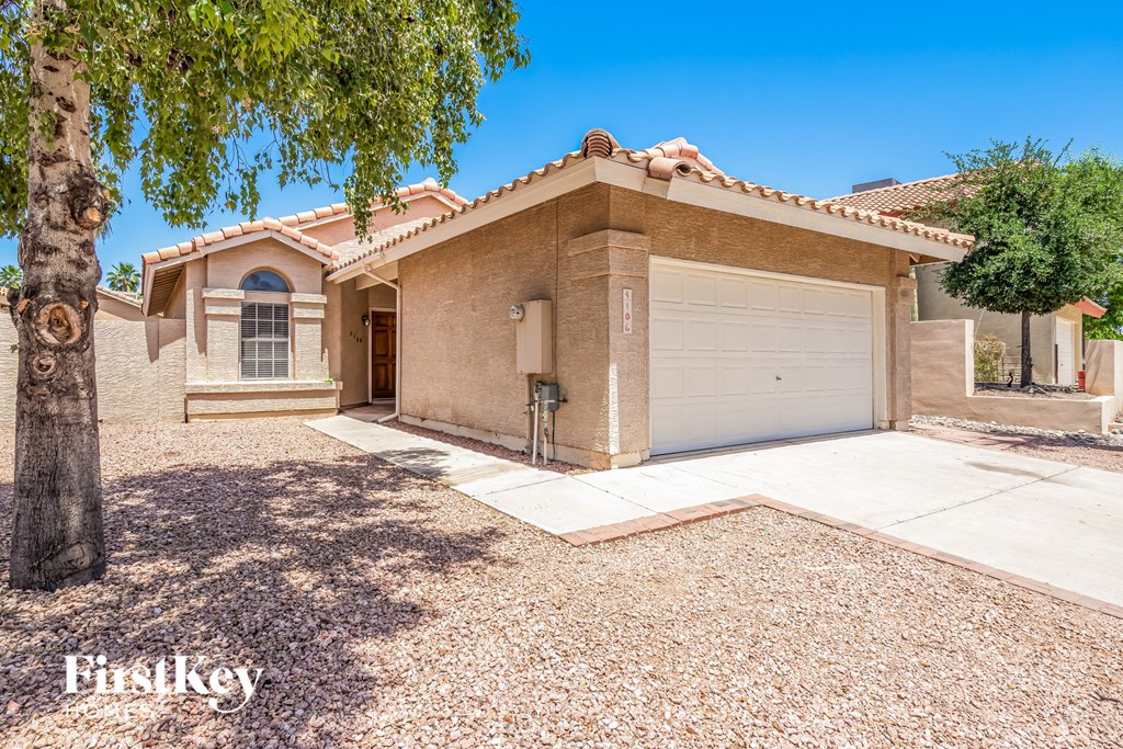 a beige brick house with a garage and a tree