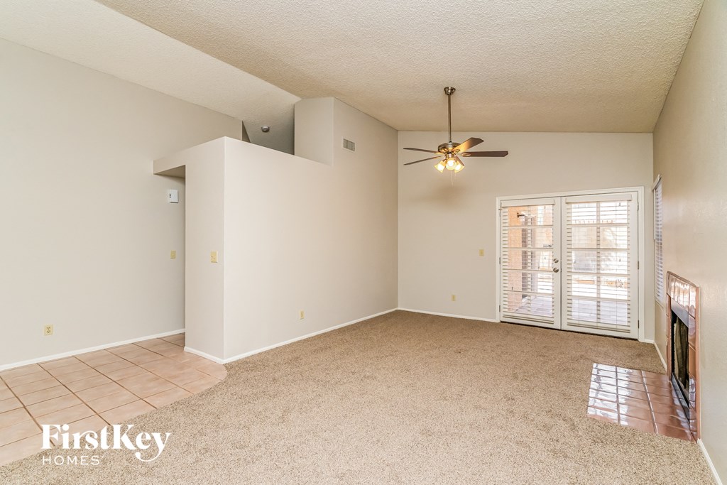 an empty living room with a ceiling fan and a window