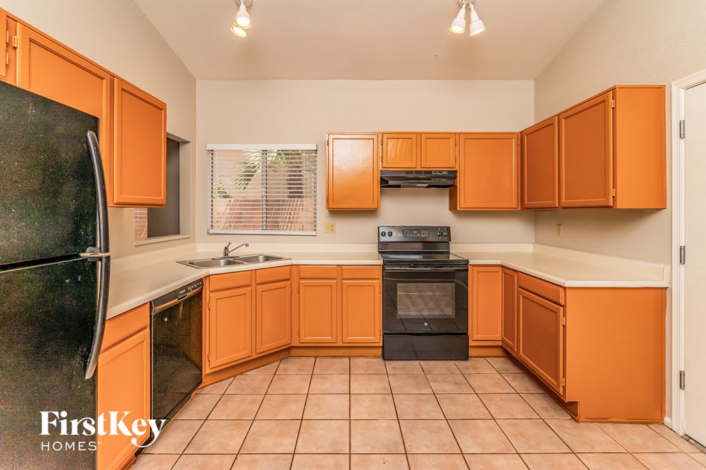 a kitchen with orange cabinets and black appliances