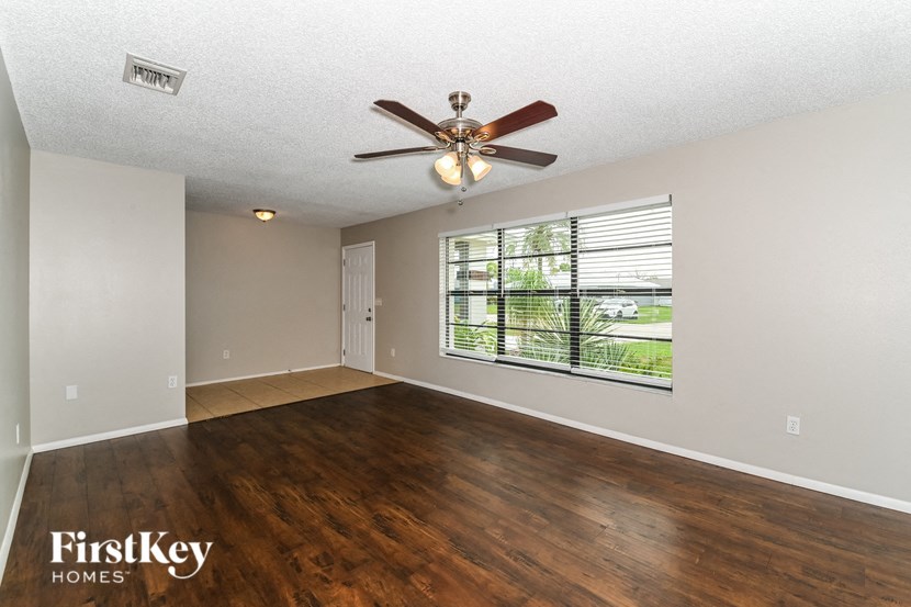 an empty living room with a ceiling fan and a large window