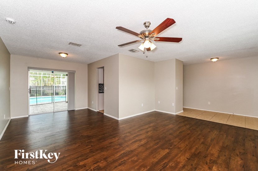 an empty living room with wood floors and a ceiling fan