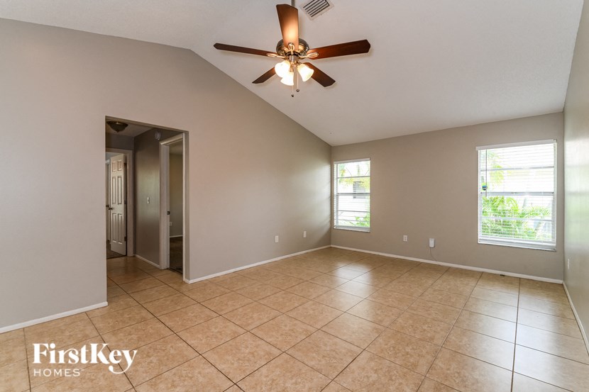 an empty living room with a ceiling fan and tile floors