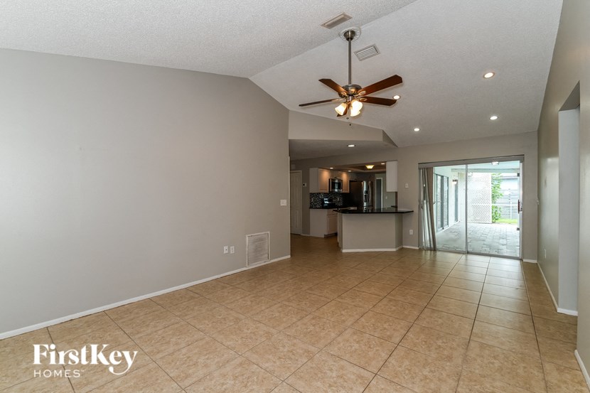 a spacious living room with tile flooring and a ceiling fan