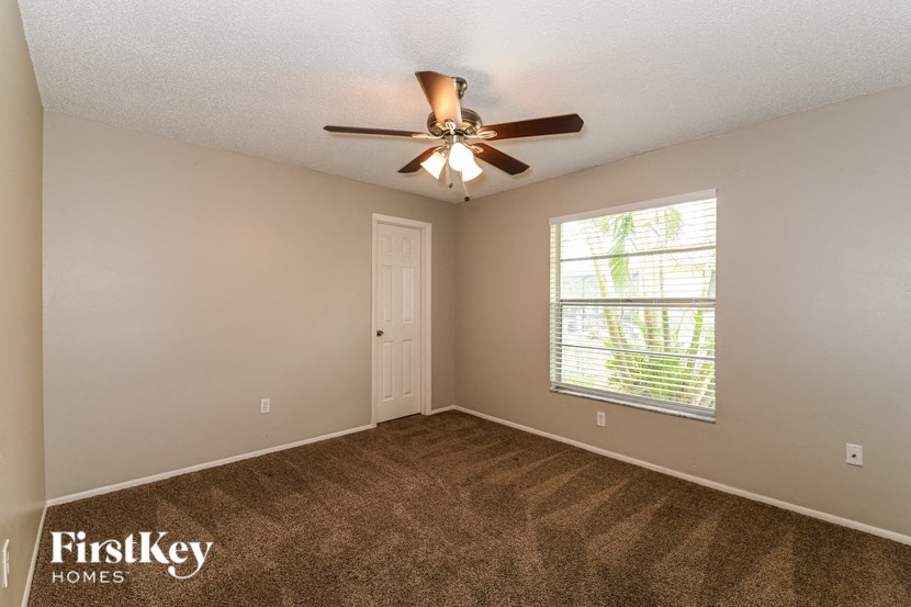 the master bedroom has a ceiling fan and a large window