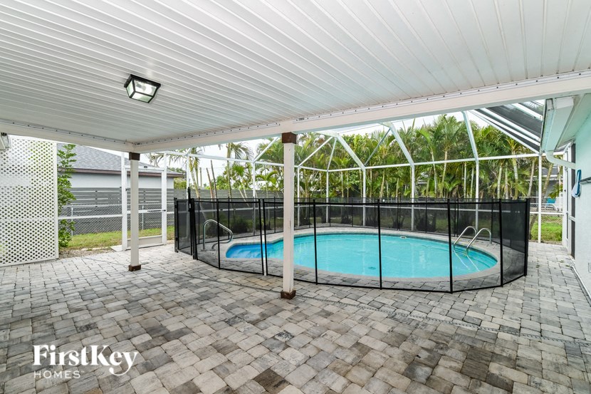 a swimming pool is under a covered patio with a wrought iron fence