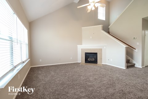 A spacious living room with a fireplace and a staircase.