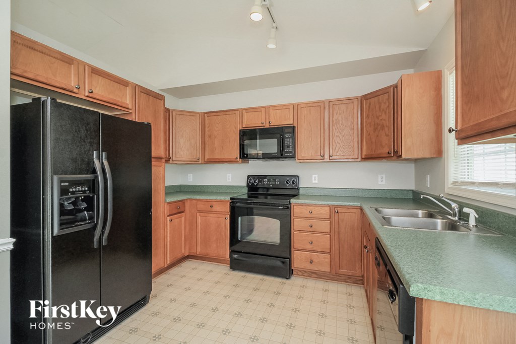a kitchen with wood cabinets and black appliances and a green counter top