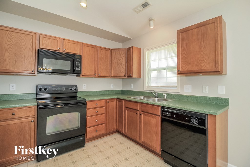 a kitchen with wood cabinets and black appliances and green counter tops