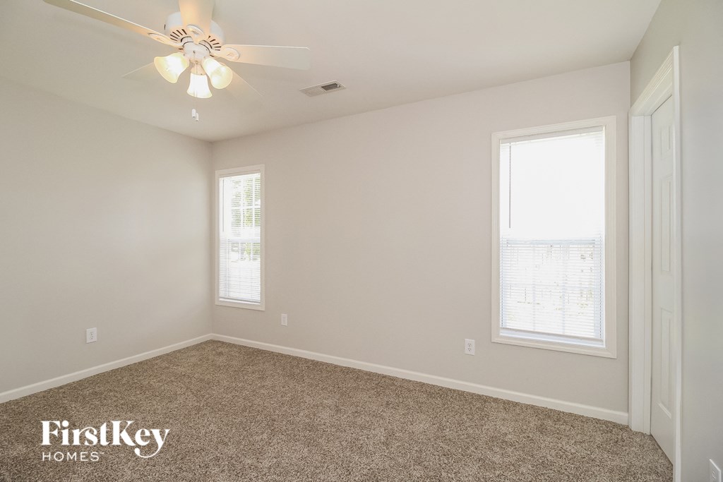 a bedroom with a ceiling fan and two windows