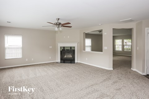A spacious living room with a fireplace and a ceiling fan.