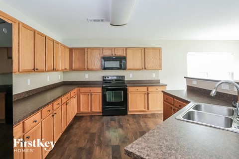 A kitchen with wooden cabinets and a black stove top oven.