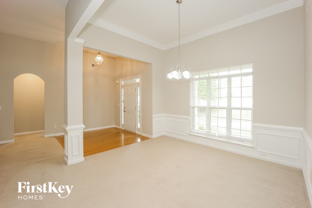 A spacious room with a large window and a chandelier hanging from the ceiling.