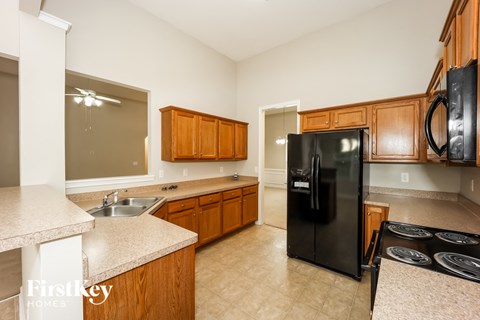 A kitchen with wooden cabinets and a black fridge.
