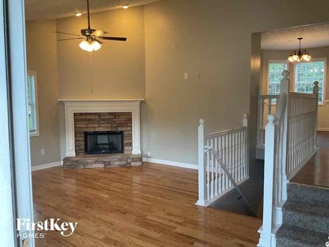 A living room with a fireplace and a ceiling fan.