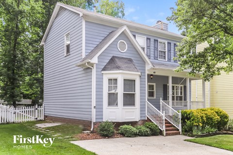 a blue house with a white front porch and a white fence