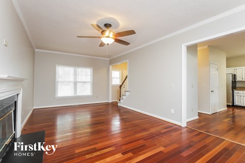 the living room and dining room with wood floors and a ceiling fan