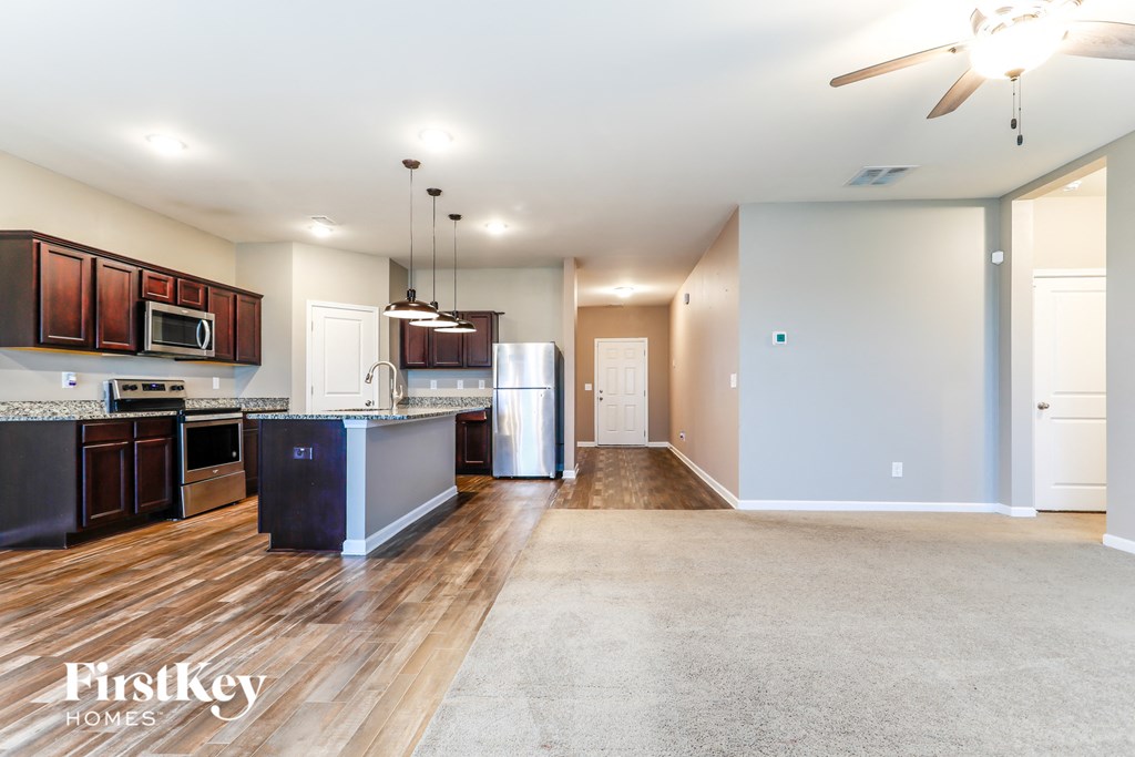 a kitchen and living room with wood flooring and stainless steel appliances