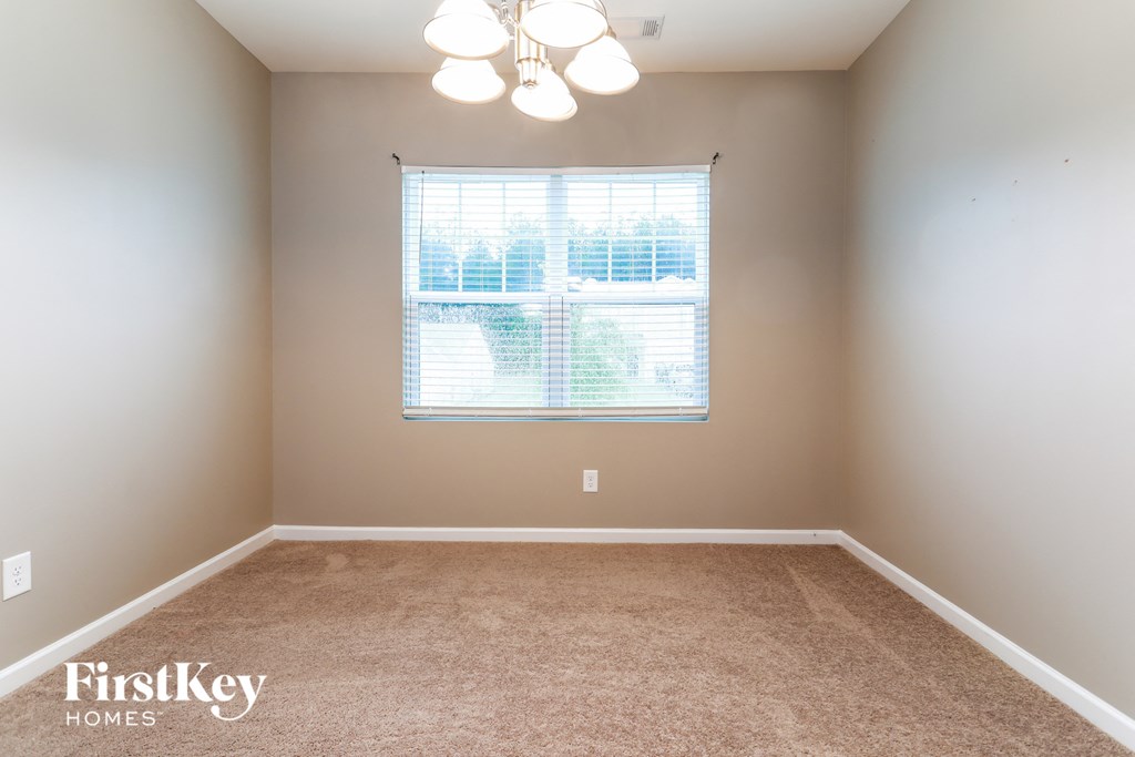 a carpeted room with a window and a chandelier