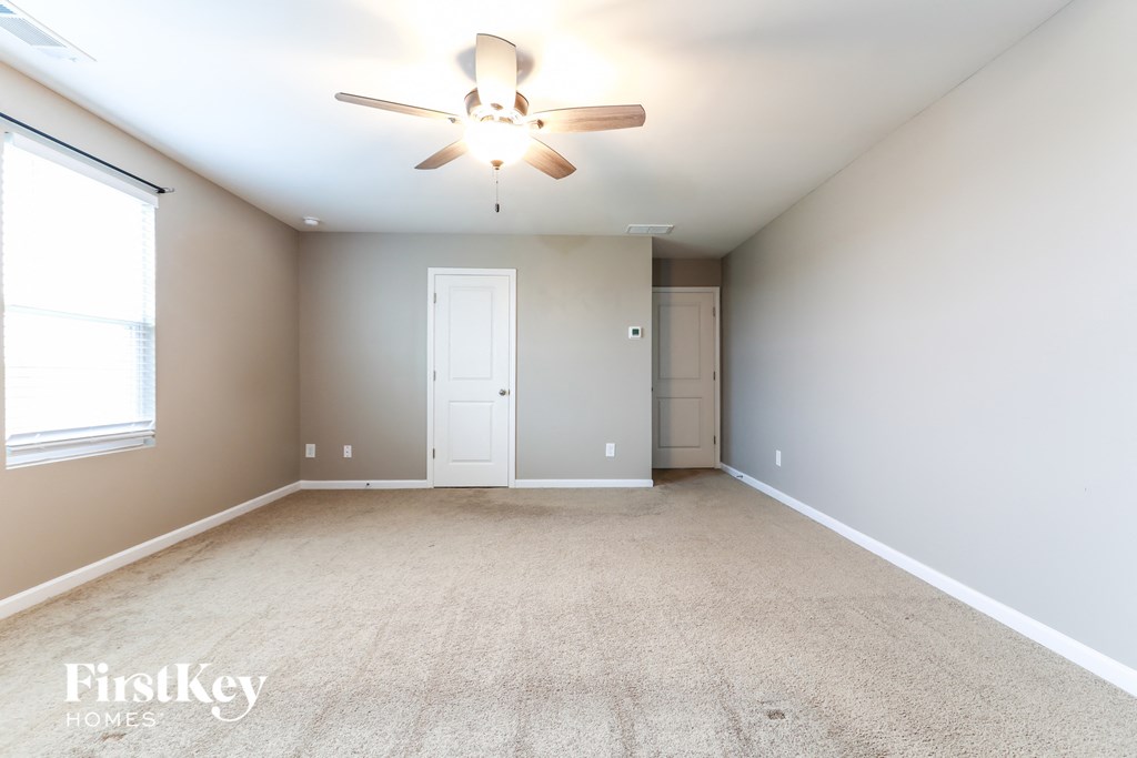 an empty living room with a ceiling fan and a window